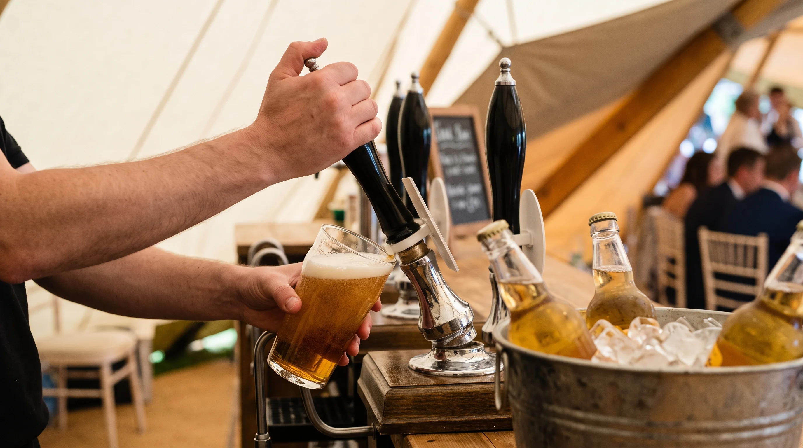 A pint of local beer being pulled at a wooden marquee bar with bottles of cider on ice beside it